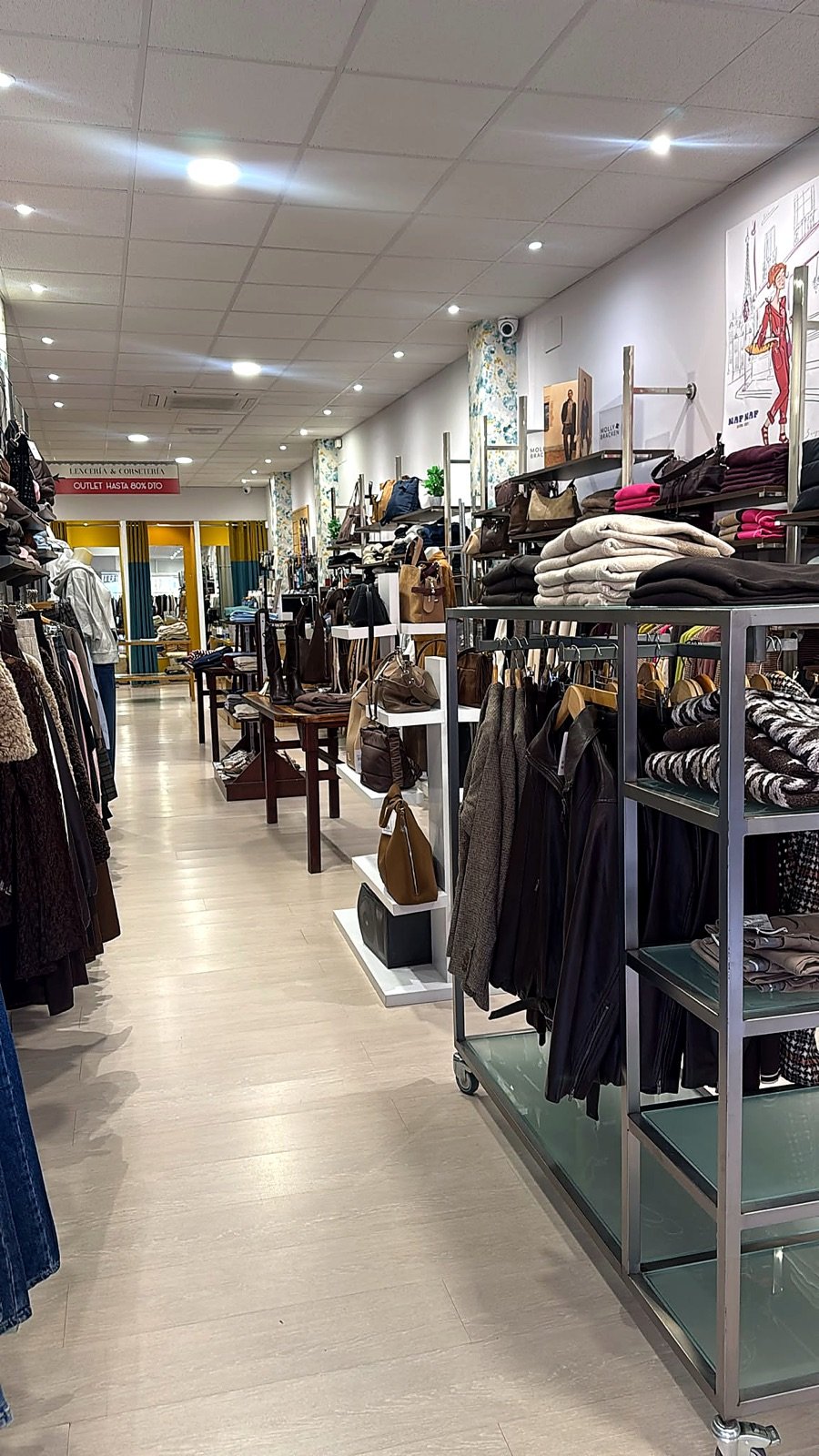 Interior de la tienda con perchas de ropa de mujer y estanterías de punto
